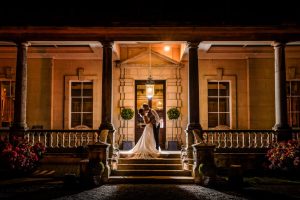 Bride and groom embracing in the orange glow of a porch at Birdsall 