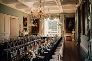 A ballroom lined with a huge L shaped table and chairs with lots of florals down the middle