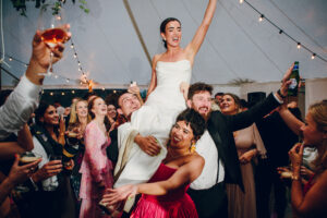 bride on shoulders of her guests at wedding party